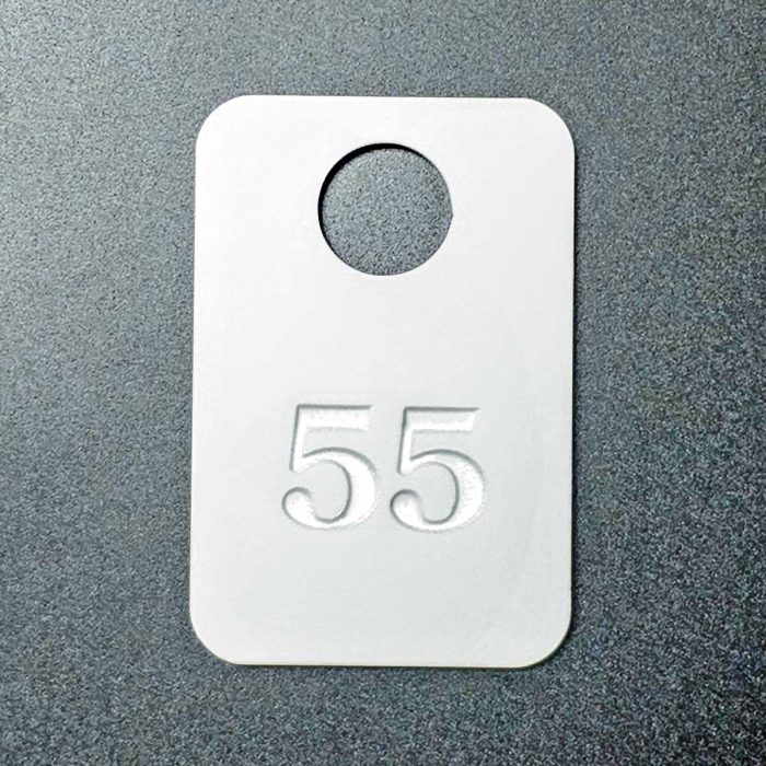 Balts akrila plastmasas garderobes numuriņš ar padziļinātu marķēšanu 1 mm uz tumša fona